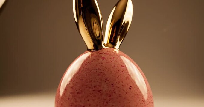Elegant pink egg-shaped object with a golden top, illuminated by a soft background light