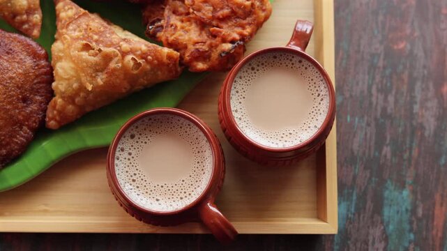 Assorted Kerala snacks Ulli vada spicy onion fritters  Parippu Vada or Paruppu Vadai made with toor dal Samosa crunchy triangular shaped wraps Neyyappam bonda and milk tea undampori. 