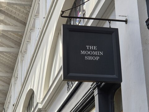 London UK 04.07.2025 The Moomin Shop sign hanging on classic white building facade with minimal black design showcasing recognizable brand identity in elegant urban shopping street environment