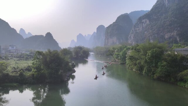 Bamboo Raft Drifting Along a Scenic Karst River Through Misty Mountains