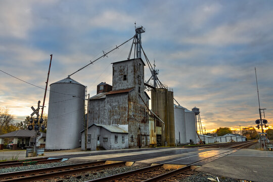 Grain elevators and railroad tracks at sunset in small town