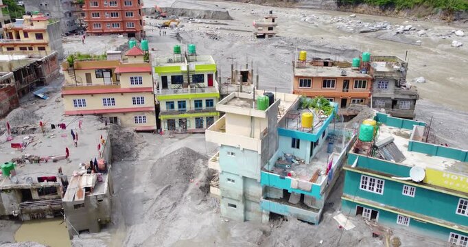 Drone shot of the Melamchi, Nepal flood aftermath showing debris, silt, and damaged riverbanks with isolated homes, highlighting fragile infrastructure and vulnerable mountain communities.