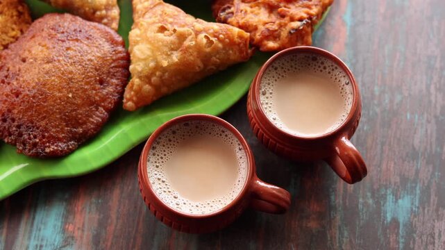 Assorted Kerala snacks Ulli vada spicy onion fritters  Parippu Vada or Paruppu Vadai made with toor dal Samosa crunchy triangular shaped wraps Neyyappam bonda and milk tea undampori. 