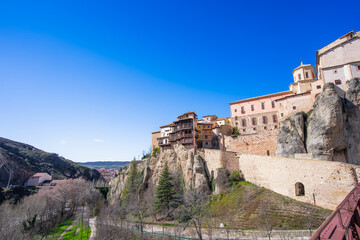 Fototapeta premium The famous Hanging Houses or Casas Colgadas perched on a cliff edge in the historic city of Cuenca, Spain, under a clear blue sky.