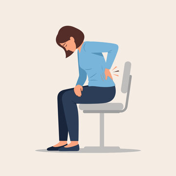 Woman sitting on chair with back pain, holding her lower back, discomfort and ache