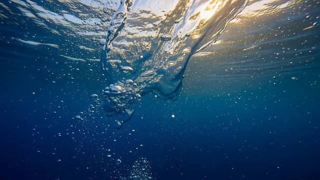 underwater diver swimming toward sunlit blue water surface