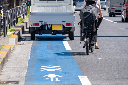 路上駐車を避けて車道に出る親子の自転車と交通リスク