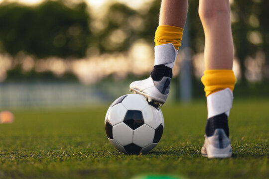 Youth Soccer Ball Control Close-Up. Kid Standing with Foot on Football During Training on Grass Field