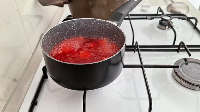 Red borscht boiling in a saucepan on gas stove, steam rising as the soup cooks, capturing the warmth, color, and traditional essence of homemade kitchen preparation