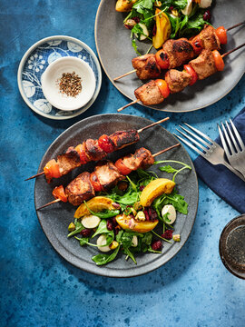Grilled chicken skewers are presented alongside a fresh salad composed of greens, tomatoes, and nuts. Perfect for restaurant menus, catering services, or healthy eating blogs