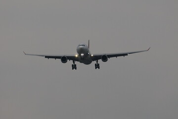 Fototapeta premium Commercial airplane landing at dusk with landing lights on.