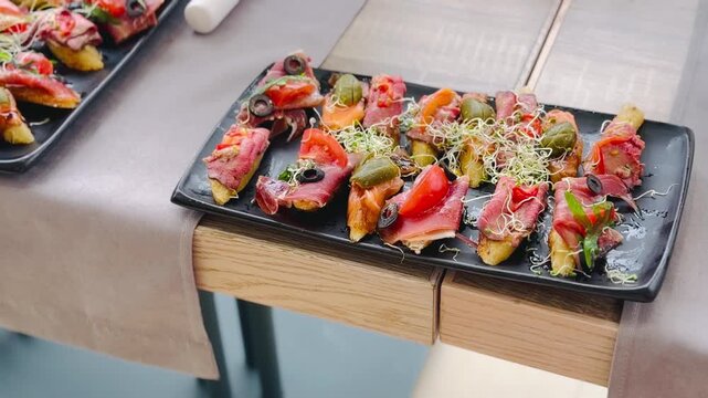 Assorted gourmet bruschettas with roast beef and prosciutto on black plate