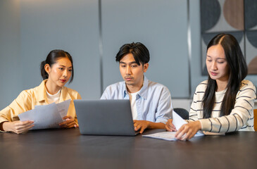 Fototapeta premium Asian digital marketing agency team analyzing SEO and ads performance on table, Young business professionals discussing campaign metrics, conversion rate and online marketing strategy concept