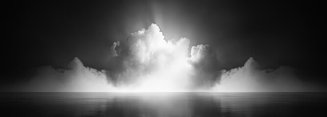 Fototapeta premium black and white seascape with a dramatic illuminated cloud bank rising over calm reflective water, misty horizon and ethereal serene mood