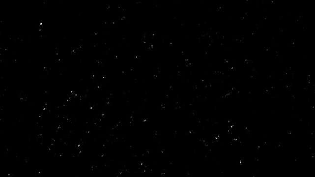 Floating white particle dust on black background creating a cosmic starfield effect. Perfect for space visuals, cinematic overlays and motion graphics projects in 4K.