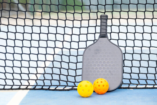 Pickleball paddle and balls resting on court
