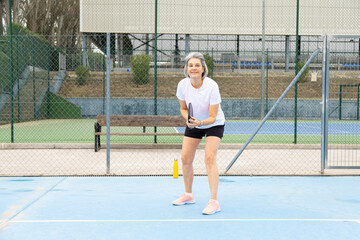 Obraz premium Mature woman playing pickleball smiling on court