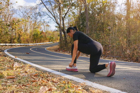 Woman runner at the racetrack tying her shoes preparing for jogging outdoor workout.