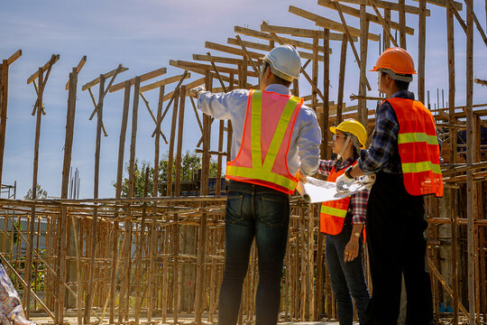Structural engineer, architect and foreman worker with blueprints discuss, plan working for the outdoors building construction site. Construction collaboration concept