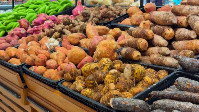 Various root vegetables and green bananas arranged on a store shelf, offering healthy food choices in the produce section.