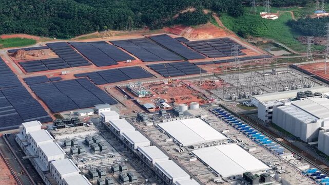 High-angle drone view of solar arrays powering expansive data center complex.