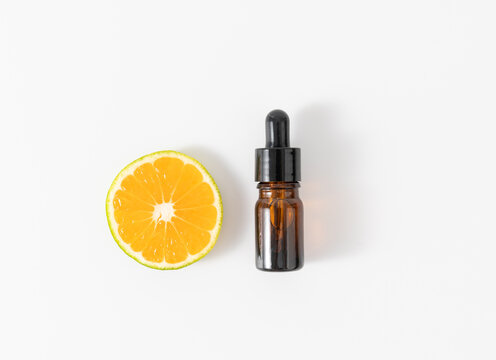 Sliced citrus and a serum dropper bottle on white background