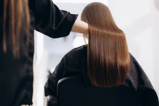 Professional hairstylist doing keratin treatment on woman's hair