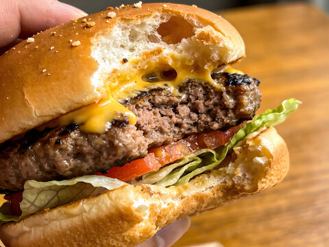 A delicious, juicy hamburger with melted cheese, fresh lettuce, and tomato, ready to be devoured on a sesame seed bun