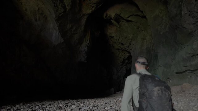 Static shot of Nam Non cave, with a man looking around at the high ceiling before walking out of frame.