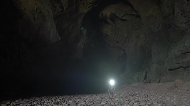 Static shot of Nam Non cave, with a man looking around at the high ceiling before walking out of frame.