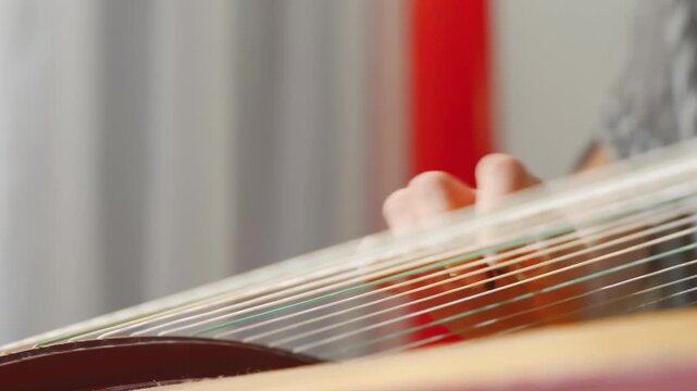 Young expertly musician playing traditional instruments, plucking strings of zither or guzheng with plectrum. The scene is peaceful, creating symphony of sound, highlight artistry, dedication to music