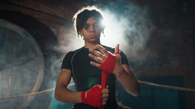 Young adult athletic man preparing to box fight, wrapping hands by elastic tape . Portrait of professional fighter in fight club, masculinity and aggression, do sport for hobby and healthy lifestyle
