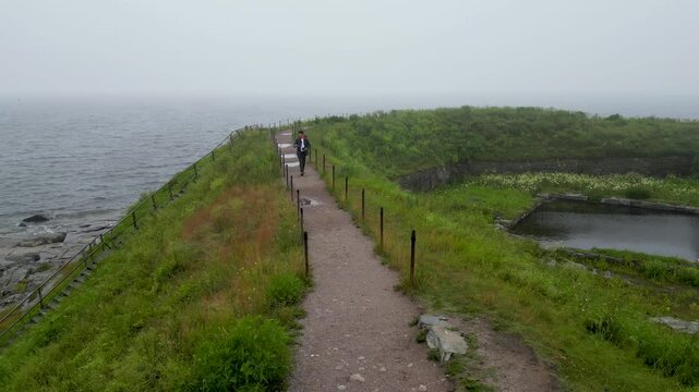 Man walking and photographing in Suomenlinna during a foggy rainy day, enjoying calm and moody surroundings