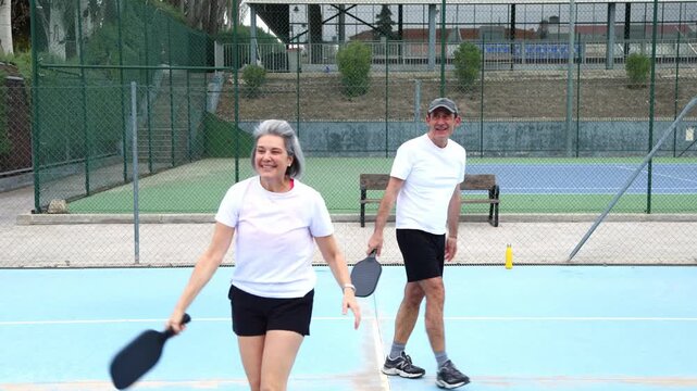 Senior couple celebrating victory on a pickleball court