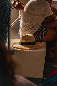 Sombrero, paja, cinta, negra, deshilachado, sol, luz, atardecer, sombras, personas, sentadas, pasajeros, barco, cubierta, viaje, transporte, verano, vacaciones, relax, hombro, brazo, reloj, camiseta