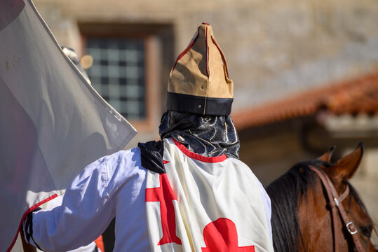 Knight Templar reenactor riding a horse from behind. The Concept of history.