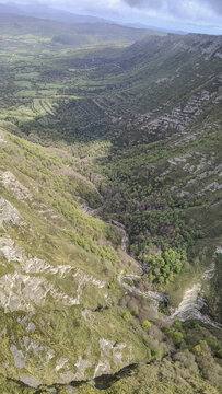Vista a&eacute;rea vertical y profunda de un ca&ntilde;&oacute;n escarpado. Sus laderas est&aacute;n cubiertas de vegetaci&oacute;n silvestre y arbustos, revelando la majestuosidad y escala del paisaje natural bajo la luz del sol.