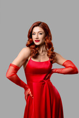 Fototapeta premium Beautiful young lady with red wavy hair on grey background