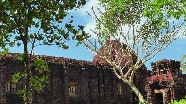 Majestic ancient Cham temple ruins surrounded by lush tropical vegetation at My Son Sanctuary near Hoi An, Vietnam. UNESCO World Heritage Site with red brick towers.