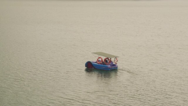A family enjoys a peaceful afternoon on a blue paddle boat on a serene lake. A perfect shot for travel, leisure, and outdoor recreation themes