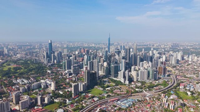 Expansive push-in aerial view of Kuala Lumpur city centre skyline featuring dense high-rise buildings, modern infrastructure, and vibrant urban landscape under clear daylight. UHD.