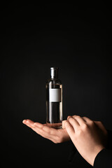 Naklejka premium Female hands with bottle of perfume on black background