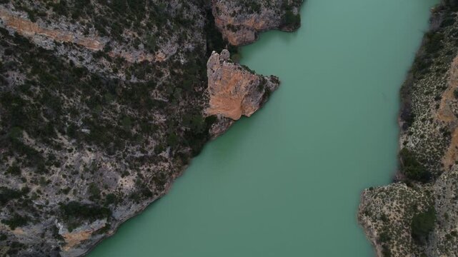 High-angle 4K drone shot flying over steep limestone cliffs of the J&uacute;car River canyon. Aerial view of turquoise waters and rugged geological formations in Castilla-La Mancha, Spain.