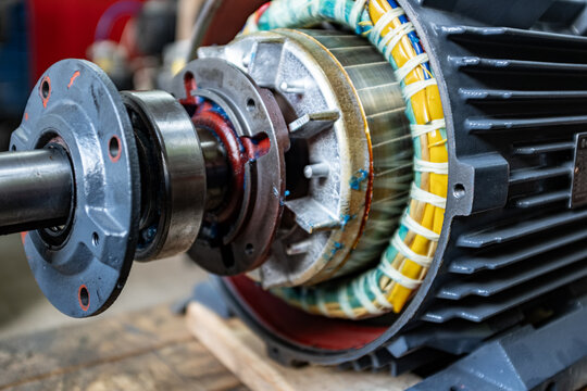 Close-up view of industrial electric motor internal structure, showing copper wire windings, stator insulation, and central ball bearing assembly for heavy-duty machinery