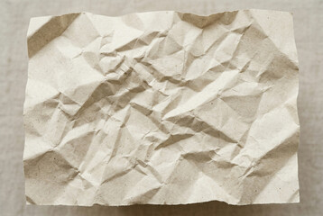 Obraz premium Crumpled beige craft paper texture for background with natural shadows and complex sheet creases organic