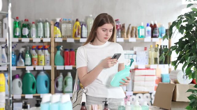 Checking expiration date of spray glass cleaner for windows - female shopper scans QR code on label of spray glass cleaner for windows using her smartphone. High quality 4k footage