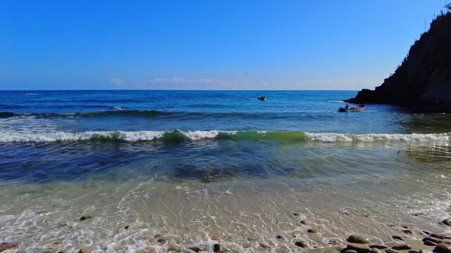 Panoramic view of the calm waters of the Choroni boardwalk, with a fishing boat leaving the pier, on the coast of Venezuela in Aragua State
