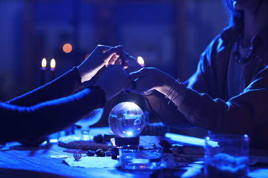 Fortune teller reading woman's palms at table