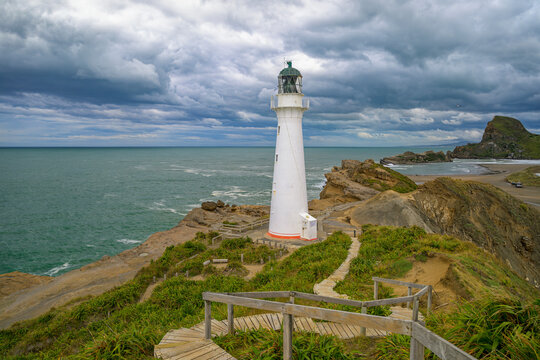 Castlepoint lighthouse standing on new zealand coastline under a cloudy sky