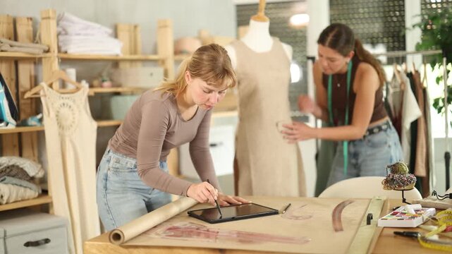 Dressmakers create clothes according to individual measurements. Fashion designer draws the design of the clothes on a tablet, and tailor checks the quality of the sample on the mannequin. High